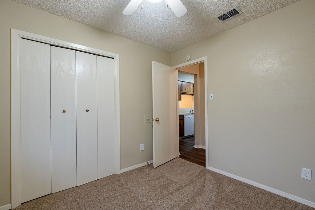 1205 Inland Greens, Unit B Austin, TX 78758 - Photo 11 of 16 Unfurnished bedroom with a textured ceiling, carpet, a closet, and ceiling fan