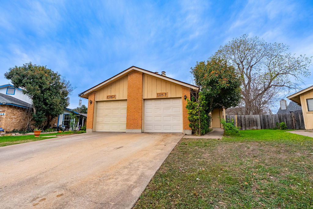 1205 Inland Greens, Unit B Austin, TX 78758 - Photo 2 of 17 a view of a house with a yard and garage