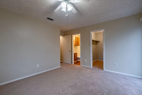 an empty room with chandelier fan and windows