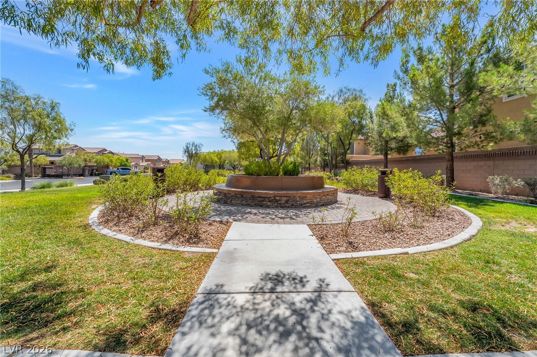 6245 Andover Wood Road Las Vegas, NV 89113 - Photo 35 of 37 A well-maintained community park offers a charming stone bench and lush landscaping under a bright sky.