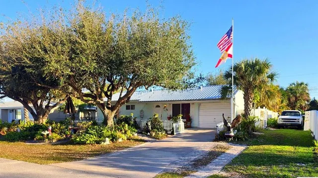 a front view of a house with yard tree and outdoor seating