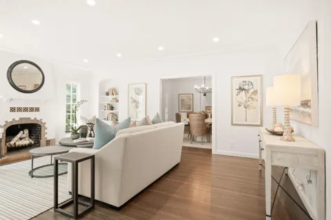 a living room with furniture a fireplace and a large mirror with wooden floor