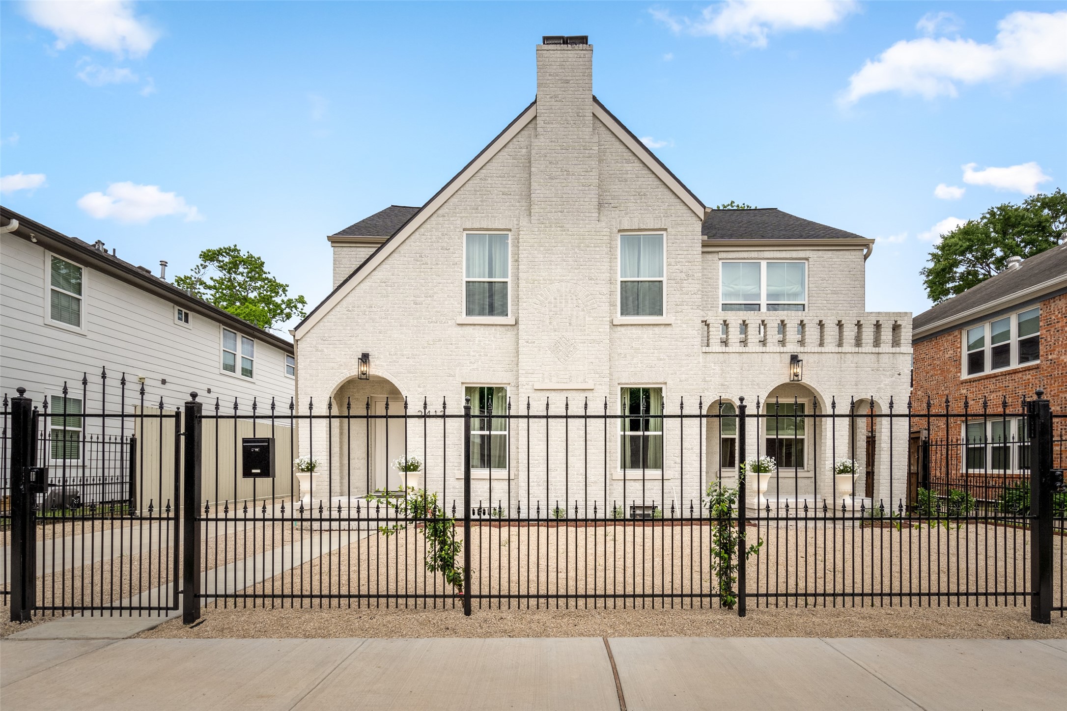 a view of a white house with iron fence