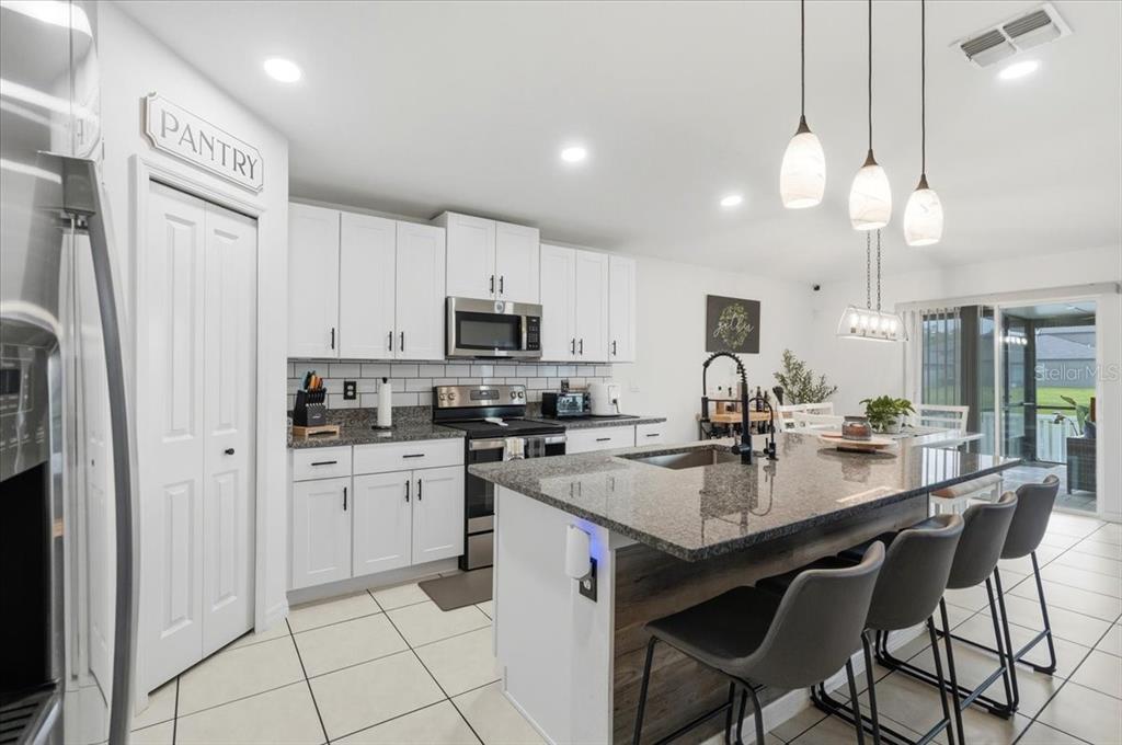 1923 Red Loop Lakeland, FL 33801 - Photo 22 of 51 a kitchen with stainless steel appliances kitchen island granite countertop a sink a stove a dining table and chairs