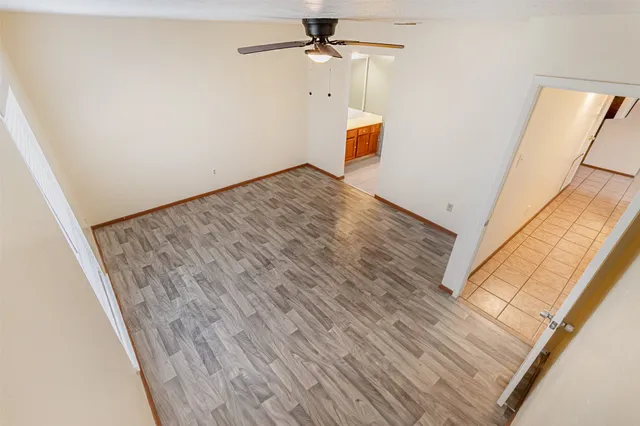 an empty room with wooden floor ceiling fan