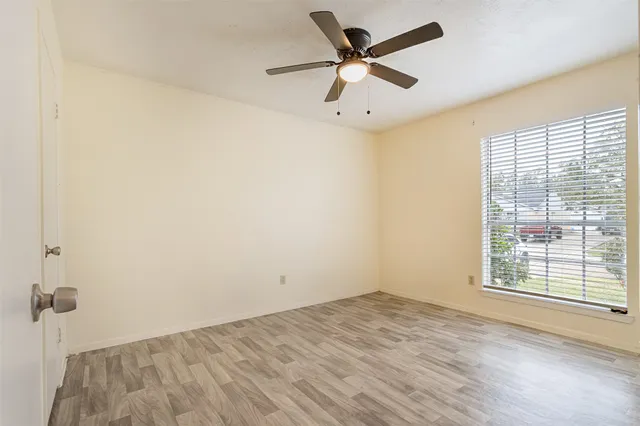 an empty room with a window and a fan