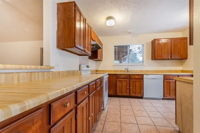 a kitchen with stainless steel appliances granite countertop a sink and stove top oven with wooden floor