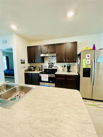 a large kitchen with stainless steel appliances granite countertop a stove refrigerator and a sink