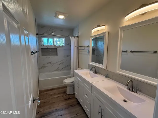 a bathroom with a double vanity sink toilet mirror and bathtub