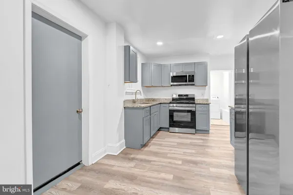 a kitchen with granite countertop a refrigerator and a stove top oven