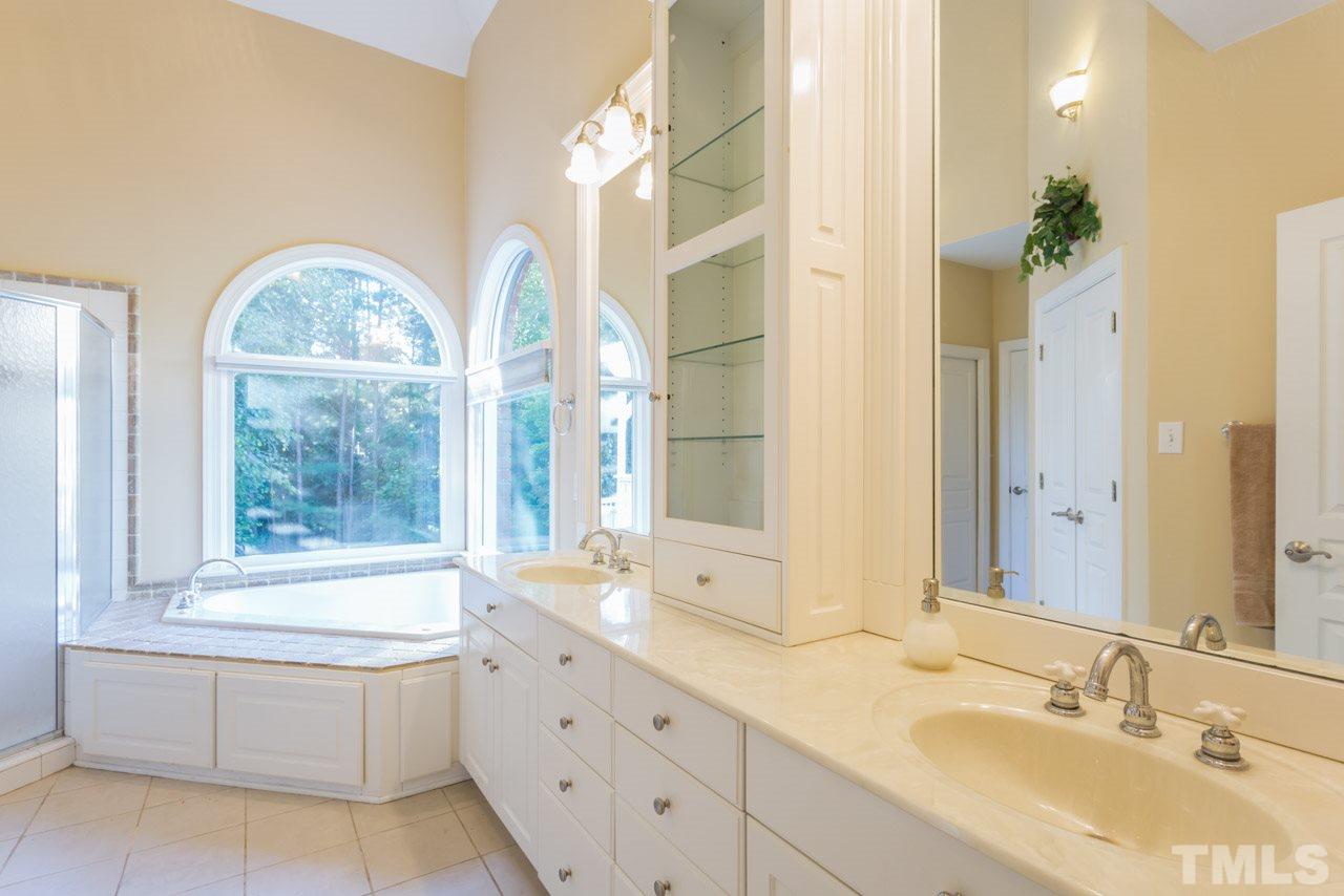 4625 Gamelyn Walk Raleigh, NC 27612 - Photo 12 of 25 a bathroom with a double vanity sink a large mirror and a bathtub