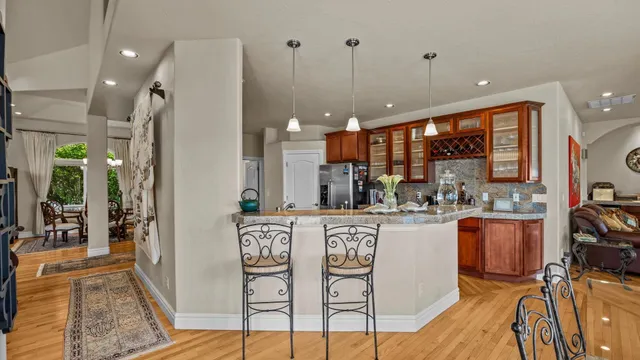 a kitchen with stainless steel appliances granite countertop a refrigerator a sink a stove and oven with wooden floor