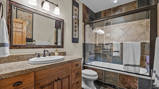 a bathroom with a sink a toilet a mirror and shower