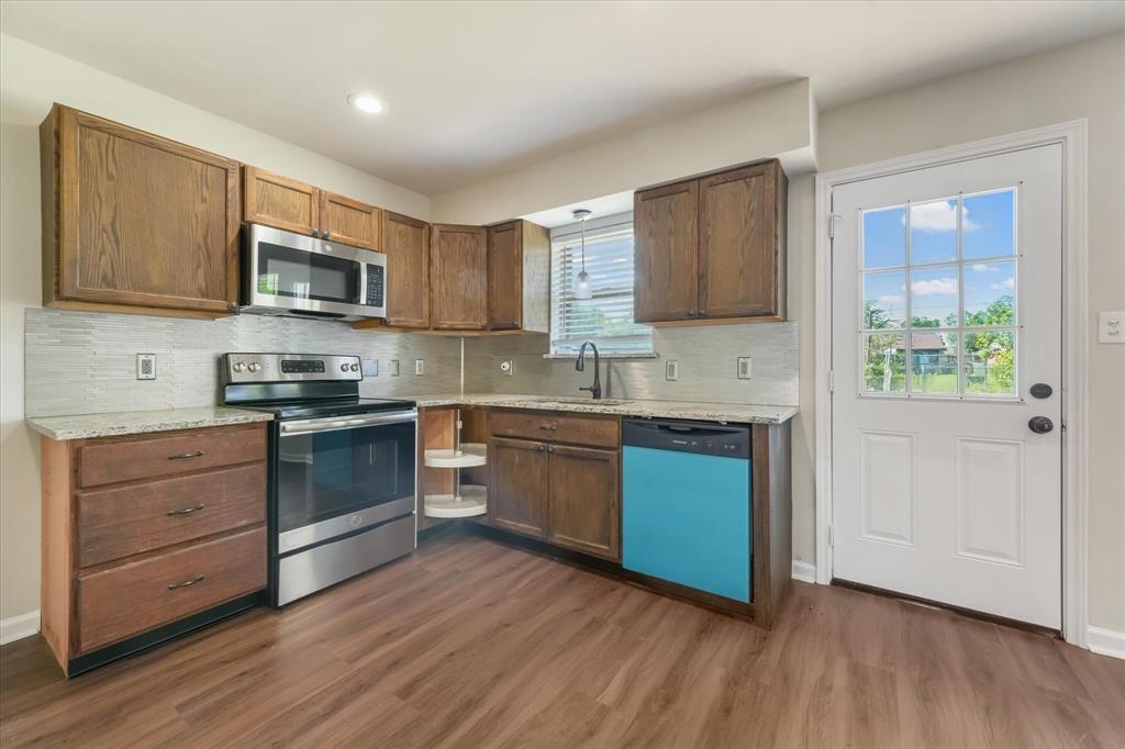 304 East Stone Road Wylie, TX 75098 - Photo 5 of 19 a kitchen with granite countertop wooden floors and stainless steel appliances