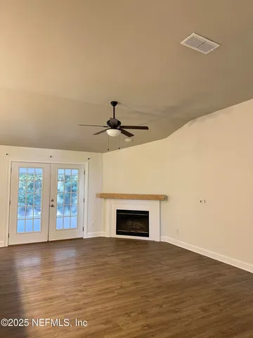 an empty room with wooden floor fireplace and windows
