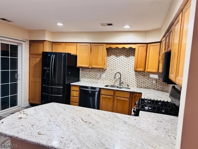 a kitchen with stainless steel appliances kitchen island granite countertop a refrigerator oven a sink with granite countertops and wooden floor