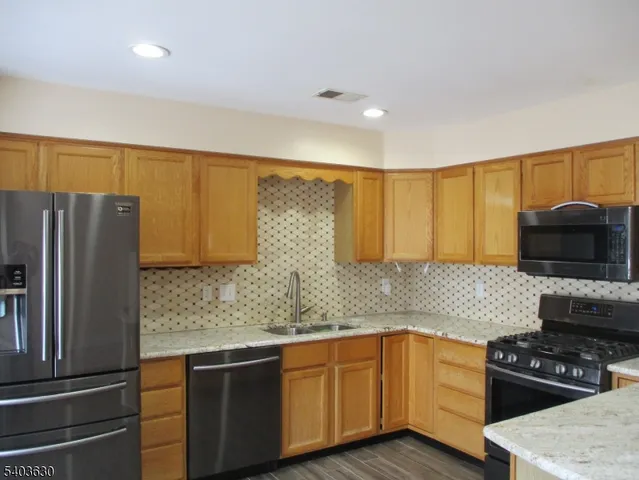 a kitchen with stainless steel appliances granite countertop a refrigerator and a sink