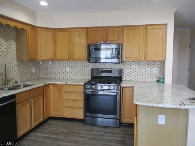 a kitchen with stainless steel appliances granite countertop a sink stove and microwave