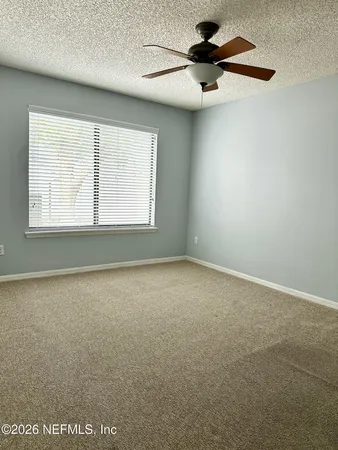 an empty room with a window and a ceiling fan