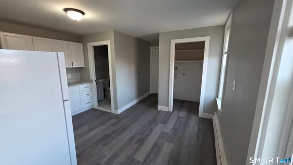 a view of a kitchen with a refrigerator and wooden floor