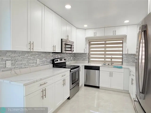 a kitchen with granite countertop white cabinets and stainless steel appliances