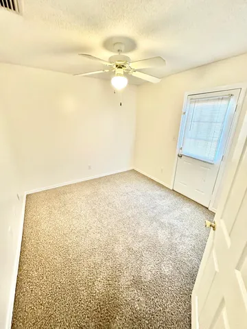 en empty room with wooden floor and fan
