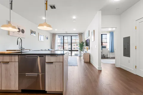 a kitchen with stainless steel appliances granite countertop a sink a stove a refrigerator and island with wooden floor