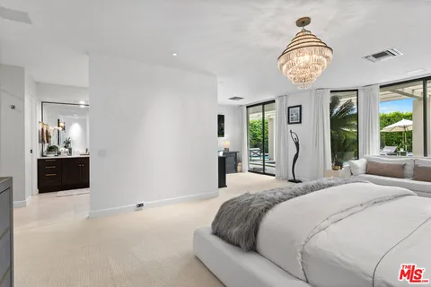 a bedroom with a large bed and a large window with balcony view