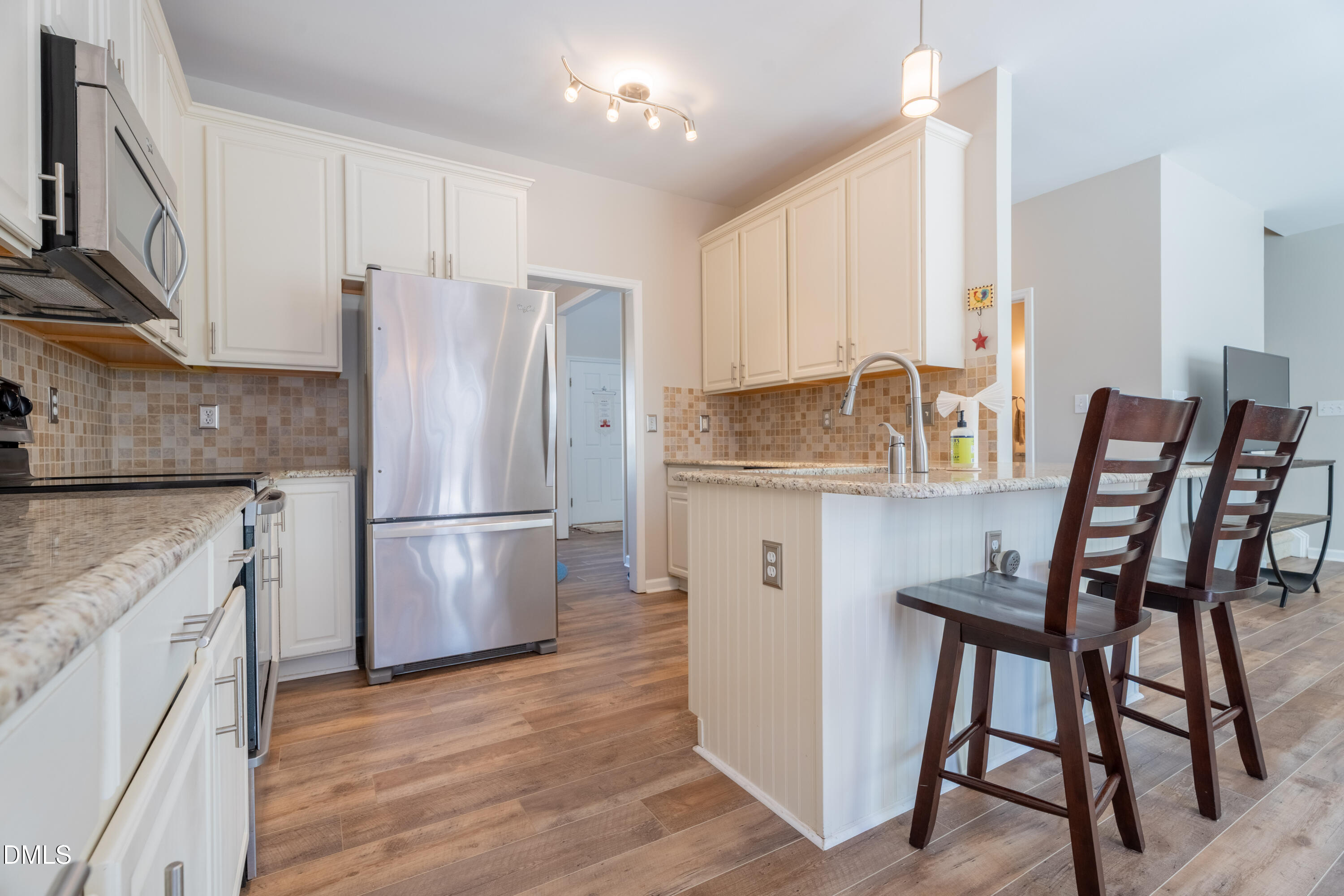 1305 Olde Walker Mill Road Apex, NC 27502 - Photo 6 of 41 a kitchen with stainless steel appliances a refrigerator a stove a sink and white cabinets with wooden floor