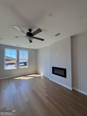 a view of an empty room with window and wooden floor
