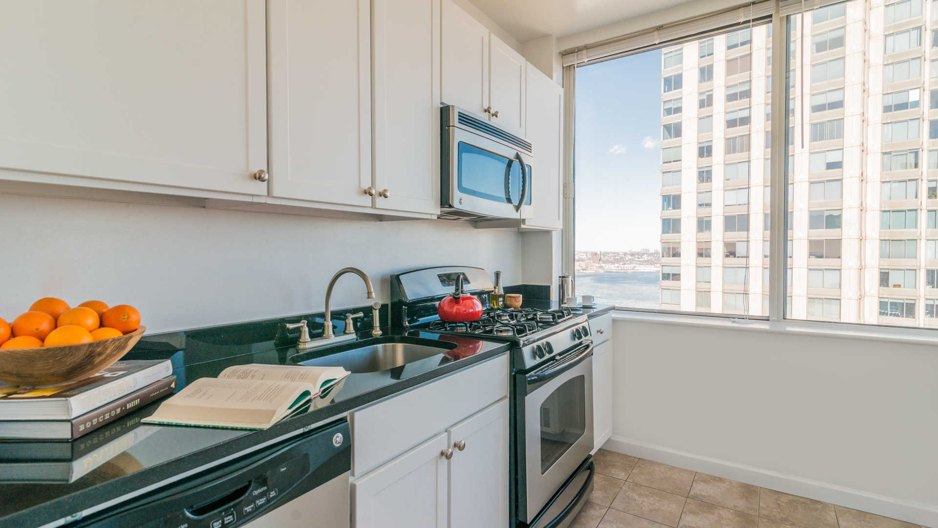 180 Riverside Boulevard, Unit 12A Manhattan, NY 10069 - Photo 6 of 11 a kitchen with stainless steel appliances granite countertop a sink dishwasher and cabinets with wooden floor