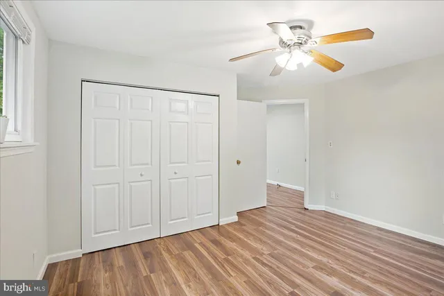 an empty room with wooden floor closet and windows