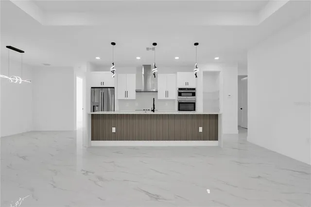 a large kitchen with stainless steel appliances a large counter top a sink a refrigerator and a window