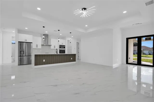 a large kitchen with stainless steel appliances kitchen island a large counter top and a refrigerator