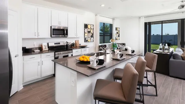 a kitchen with stainless steel appliances a stove a sink a microwave a dining table and chairs