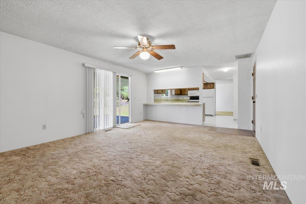 1311 North Middleton Road Nampa, ID 83651 - Photo 42 of 49 Open-concept living area featuring a ceiling fan with integrated lighting, sliding glass door access to the exterior, and carpeting