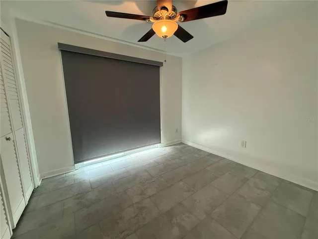 an empty room with a chandelier fan and closet