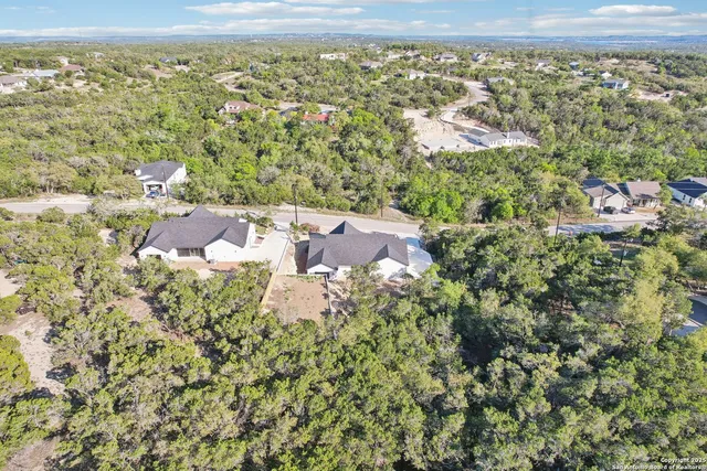 an aerial view of residential houses with outdoor space and trees