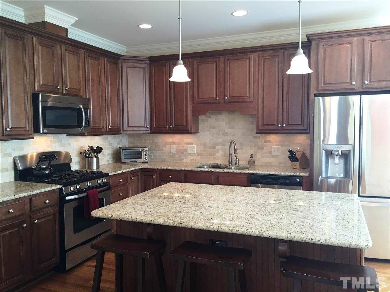 1307 Ileagnes Road Raleigh, NC 27603 - Photo 11 of 24 Great gourmet kitchen featuring stainless appliances, including a gas range, microwave, dishwasher and double stainless steel sink with disposer. Custom 42" glazed cabinets with crown molding. Granite counter tops and tiled backsplash. Kitchen