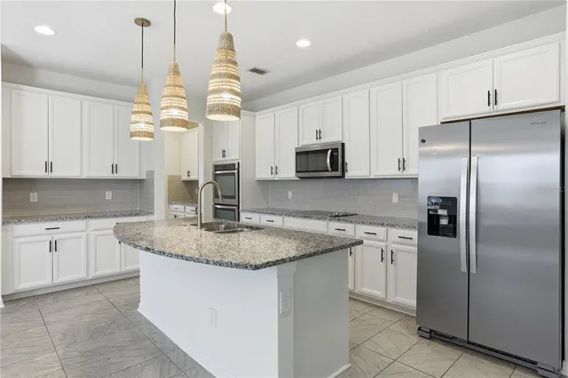 a kitchen with stainless steel appliances granite countertop a sink a stove and a wooden cabinets