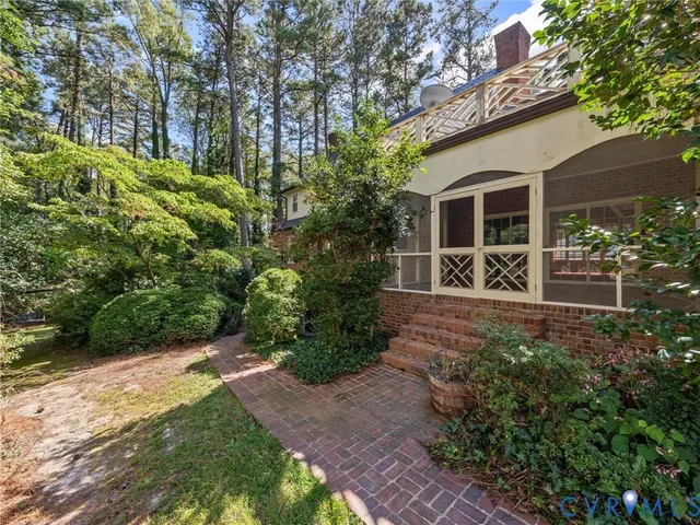 a pathway of a house with potted plants and large trees