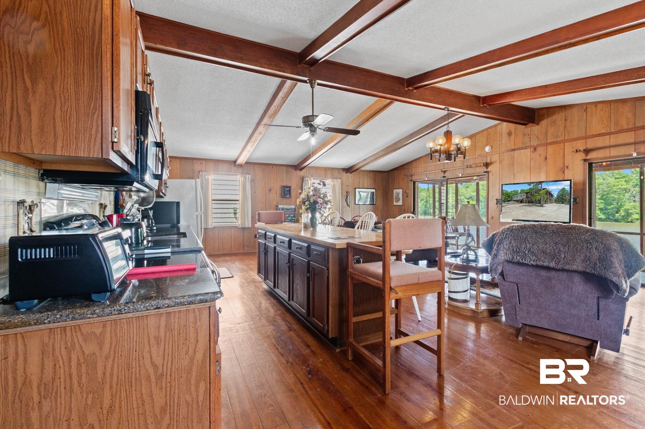 8153 Bryant's Lndg Road Stockton, AL 36579 - Photo 24 of 87 Open-concept living space with vaulted ceilings, exposed wood beams, wood-finish flooring, and a central kitchen island