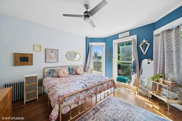 a bedroom with a bed a dresser and wooden floor