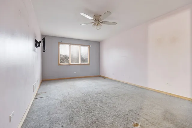 an empty room with a ceiling fan and windows
