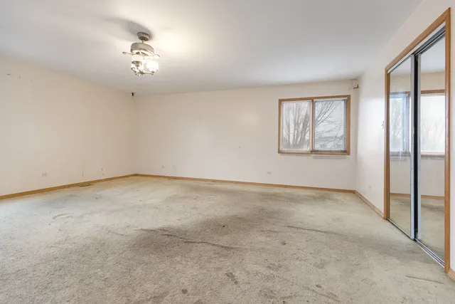 an empty room with windows and chandelier fan