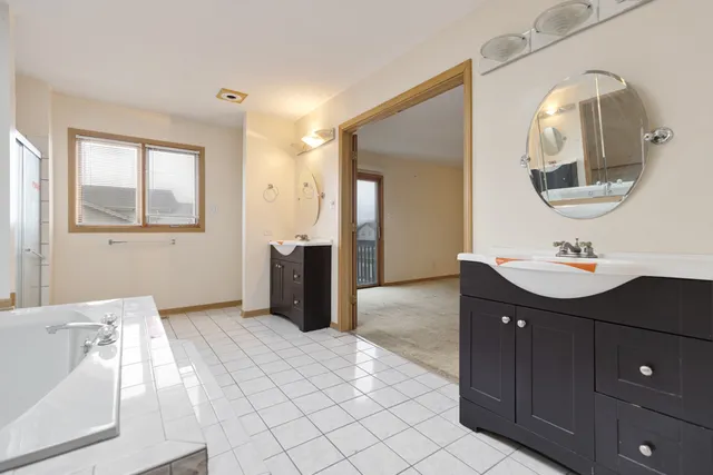 a spacious bathroom with a double vanity sink mirror and bathtub