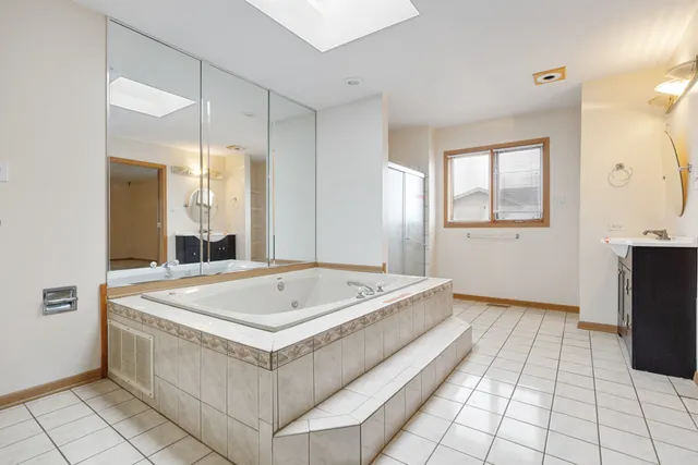 a spacious bathroom with a tub a sink and a mirror