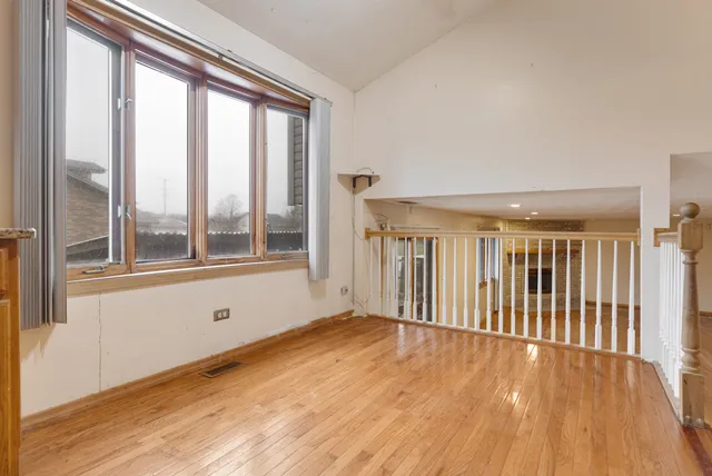a view of an empty room with wooden floor and windows