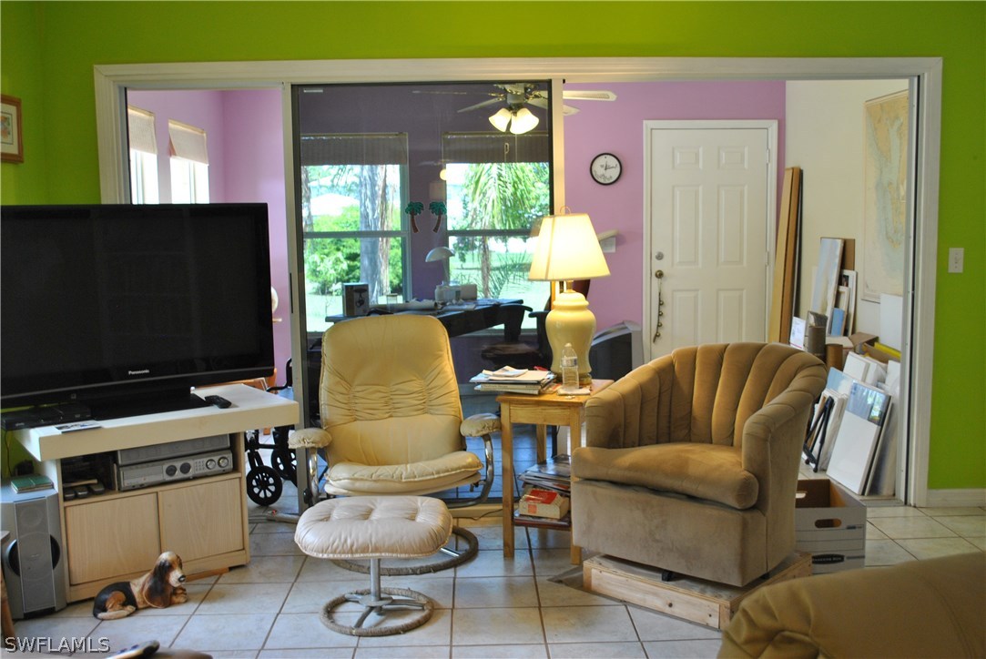 5824 Mackerel Road Bokeelia, FL 33922 - Photo 11 of 25 a living room with furniture a flat screen tv and a floor to ceiling window