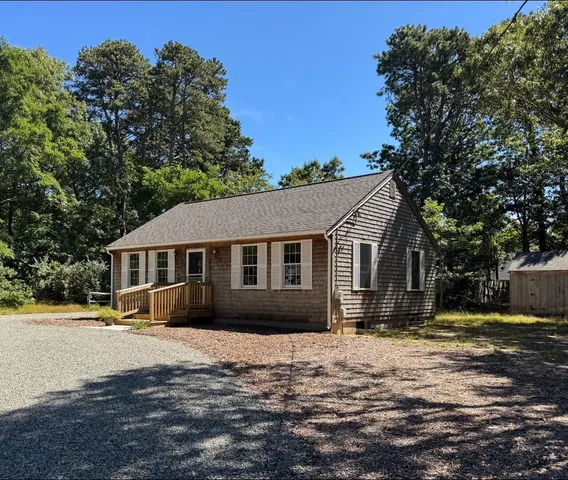 a front view of a house with a yard covered with trees
